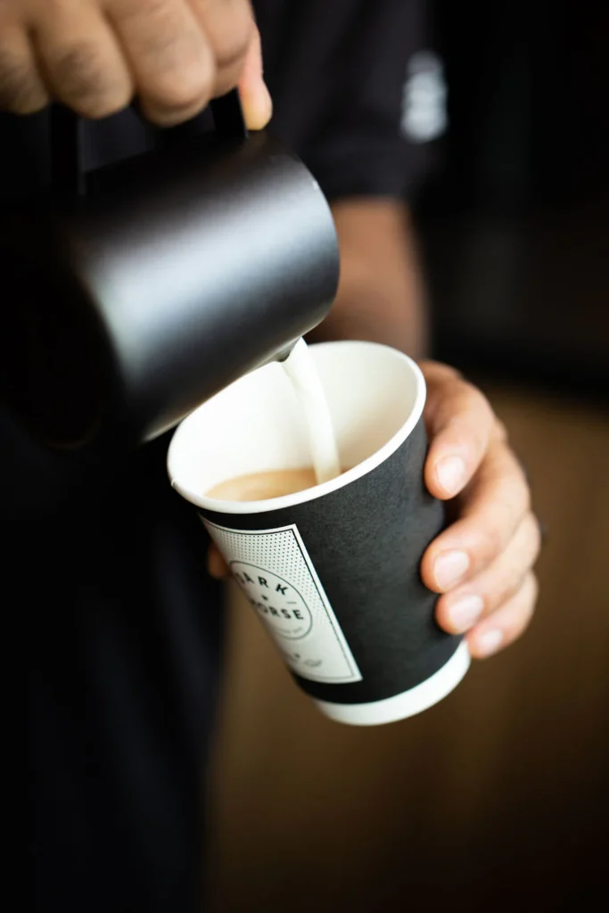 Dark Horse Espresso | Close up shot of barista pouring a latte reflecting Dark Horse’s craft-forward coffee service. | Homes Almanac