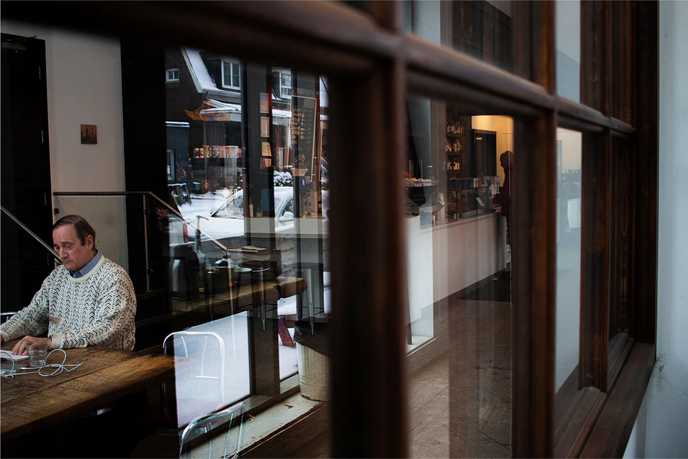 Dark Horse Espresso | Shot through a window of a man sitting at a table | Homes Almanac