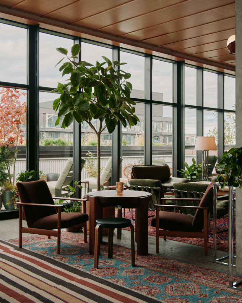 Evangeline Rooftop | Daytime shot showcasing floor to ceiling windows and cozy seating with patterned rugs | Homes Almanac