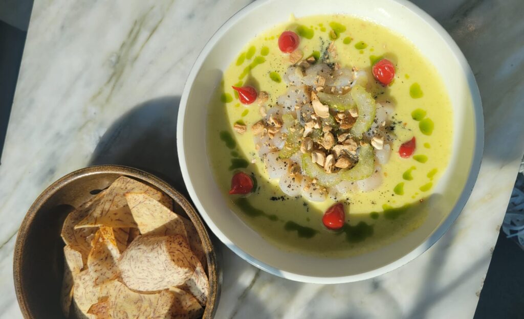 The Rooftop at the Broadview Hotel | Overhead shot of scallop ceviche in a bright yellow sauce with red pepperoncini and a bowl of taro chips | Homes Almanac