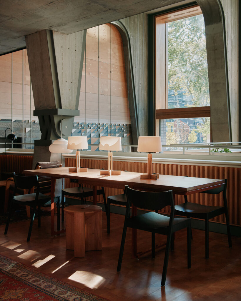 King and Portland | Brightly lit interior of Ace Hotel Lobby with a oak wood shared desk and black chairs | Homes Almanac
