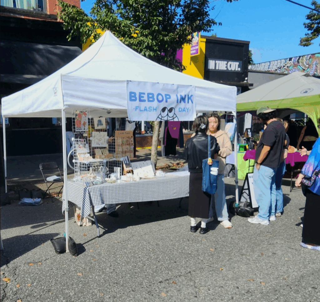 Bebop Ink Vancouver | A white tent with Bebop Ink merch at a street festival | Homes Almanac