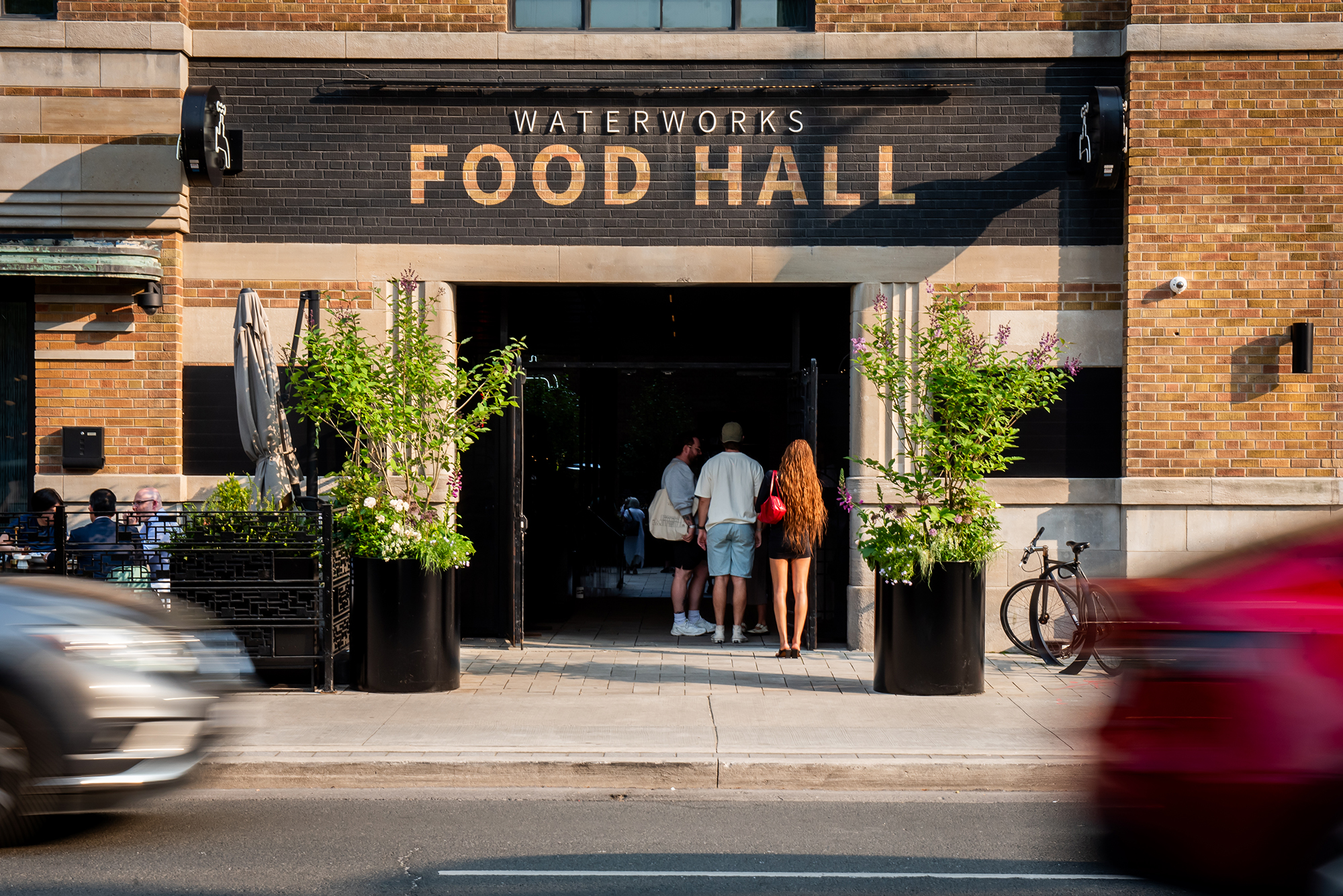 Waterworks | Sunny day with brick facade exterior with food hall painted over open doors | Homes Almanac