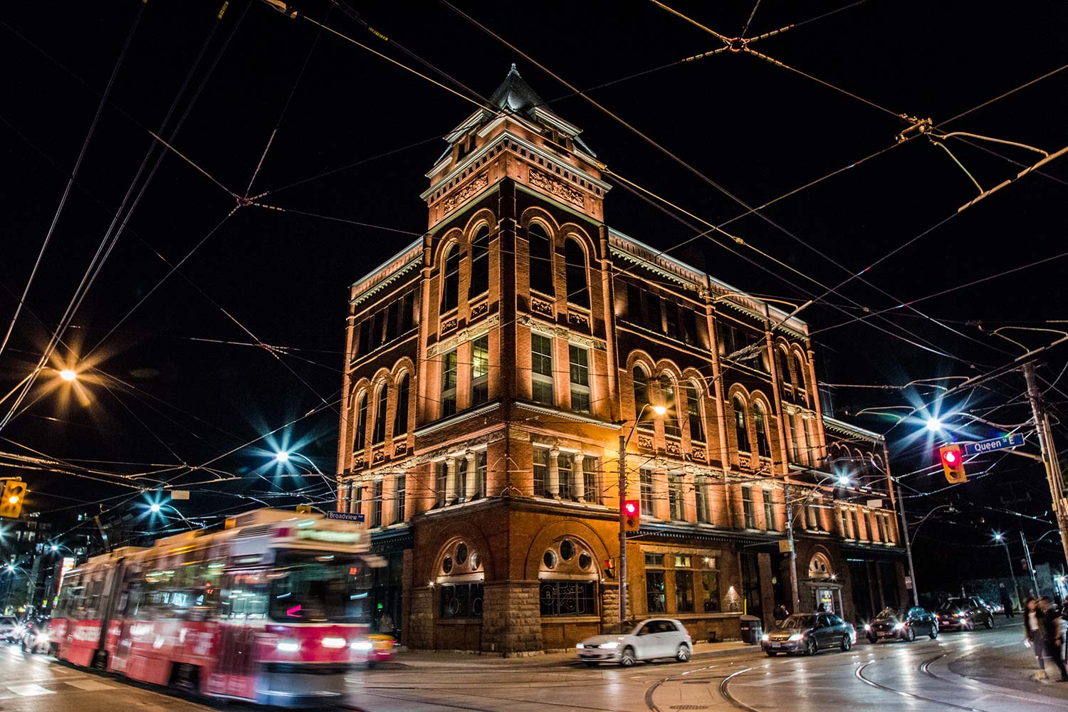 The Broadview Hotel | Night time exterior shot of The Broadview Hotel's brick facade lit up and a bus passing by | Homes Almanac