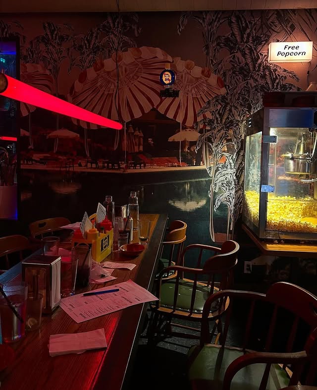 Pennies Toronto | Moody and dimly lit interior with a popcorn machine to the right and long table and chairs to the left | Homes Almanac