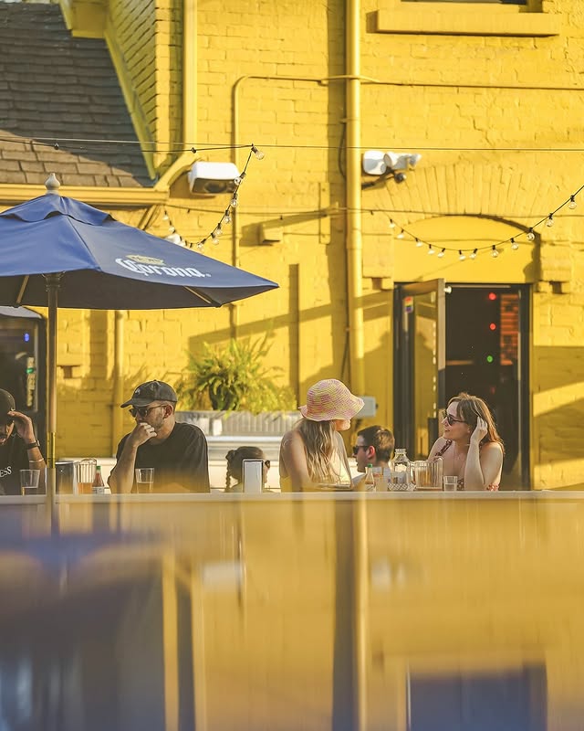 Pennies Toronto | People sitting outside on the patio against a yellow brick facade building | Homes Almanac
