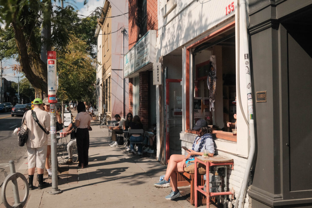 Rooms Coffee on Ossington | White storefront with people sitting outside | Homes Almanac