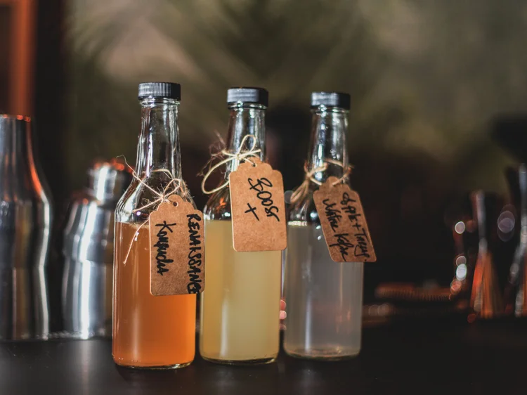 fermentation cocktails toronto | three glass bottles with various fermented liquids inside | Homes Almanac