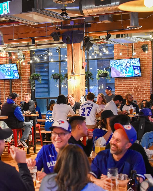 Left Field Brewery in Leslieville | Brightly lit bar with people sitting at wooden tables ad chairs | Homes Almanac