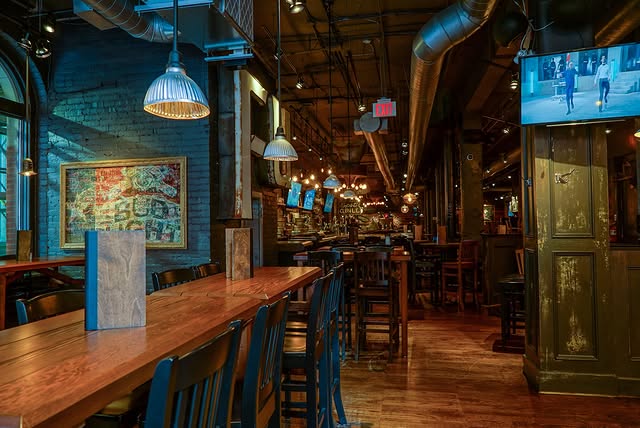 The Loose Moose | Dimly lit sports bar with wood tables and chairs | Homes Almanac