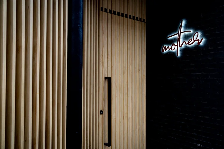 fermentation cocktails toronto | entrance of Mother with oak wood slats and a minimal sign | Homes Almanac