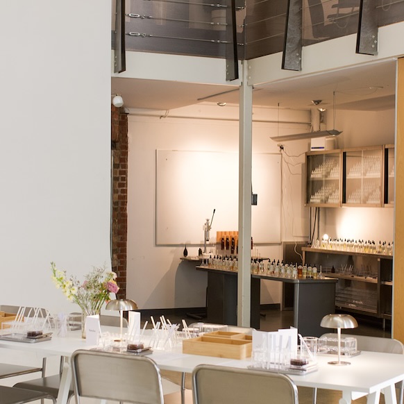 Ratelier Trinity Bellwoods | Perfumery bottles on workbenches and white table with metal chairs | Homes Almanac