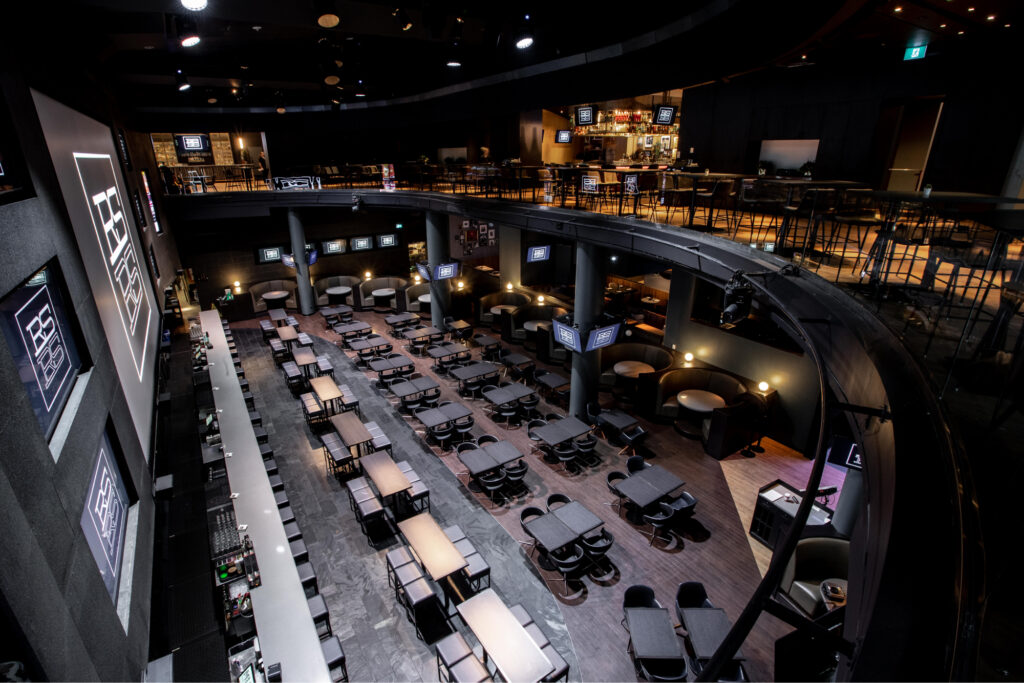 Real sports bar & grill | A dimly lit sports bar with floor to ceiling screens and tables and chairs | Homes Almanac