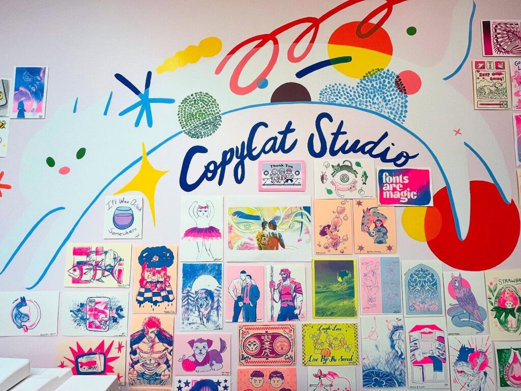 Colourful risograph prints by CopyCat Studio | Wall covered with colourful risograph prints and the logo for 'CopyCat Studio' | Homes Almanac