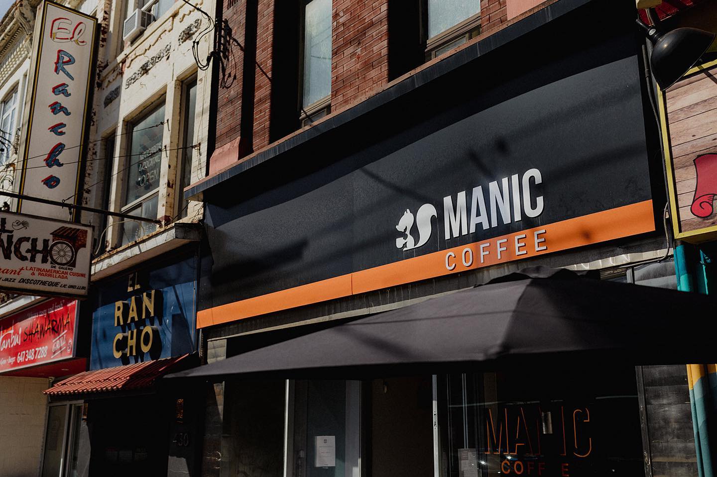Manic Coffee | A black awning with white and orange logo | Homes Almanac