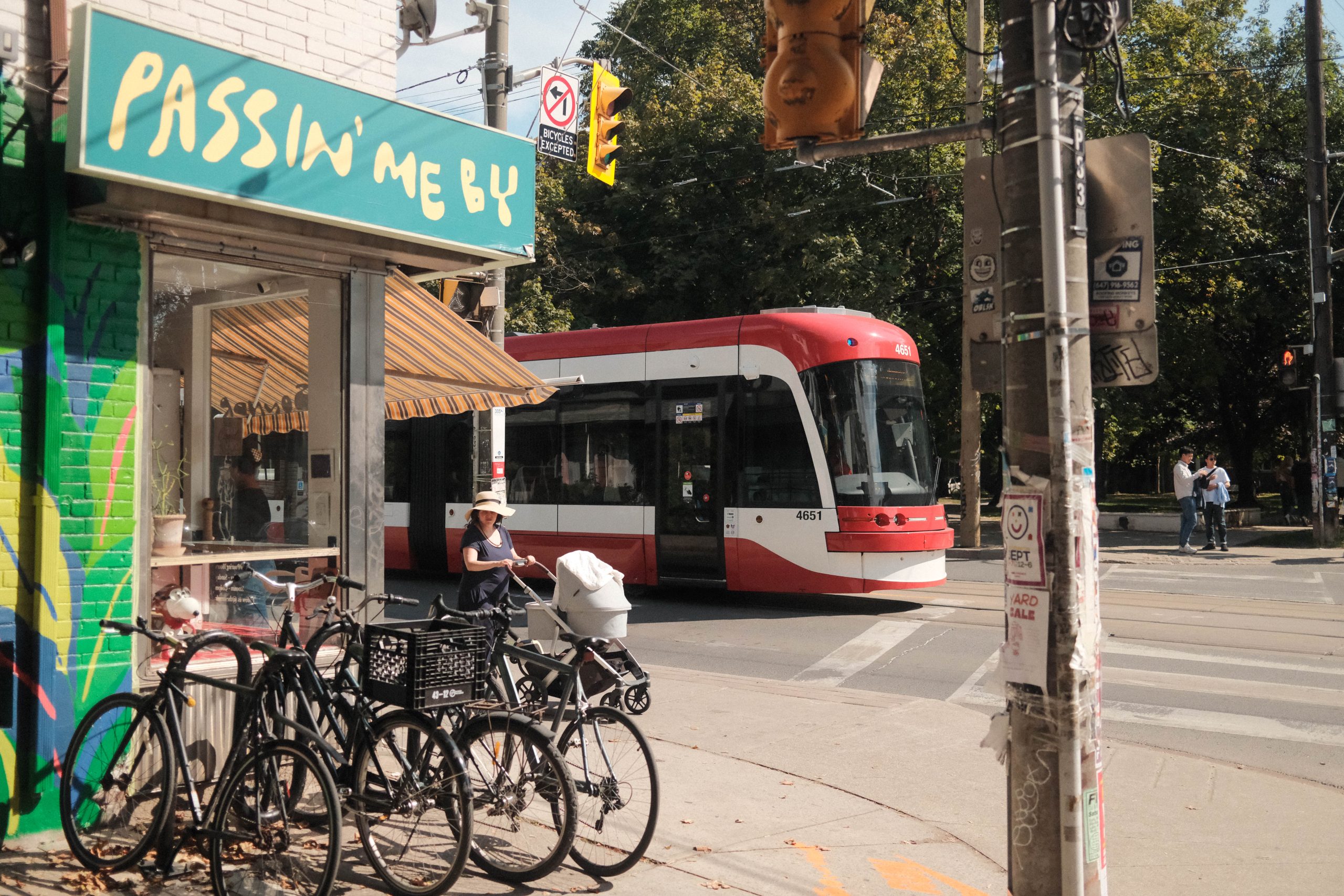 Vintage and Resale Shopping in Trinity Bellwoods | Sunny street corner with red TTC train driving by and bikes parked outside a coffee shop | Homes Almanac