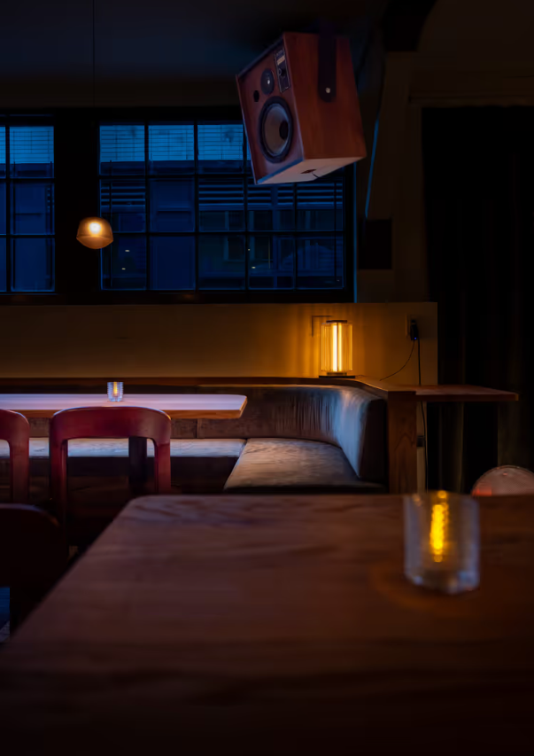 A table and booth with a speaker in view at Osteria Otto restaurant | Osteria Otto Mount Pleasant | Homes Almanac