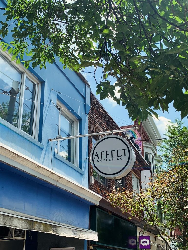 Affect Coffee | A blue exterior with white circle sign that says "Affect Coffee" with a lush tree branch overhead on a sunny day | Homes Almanac