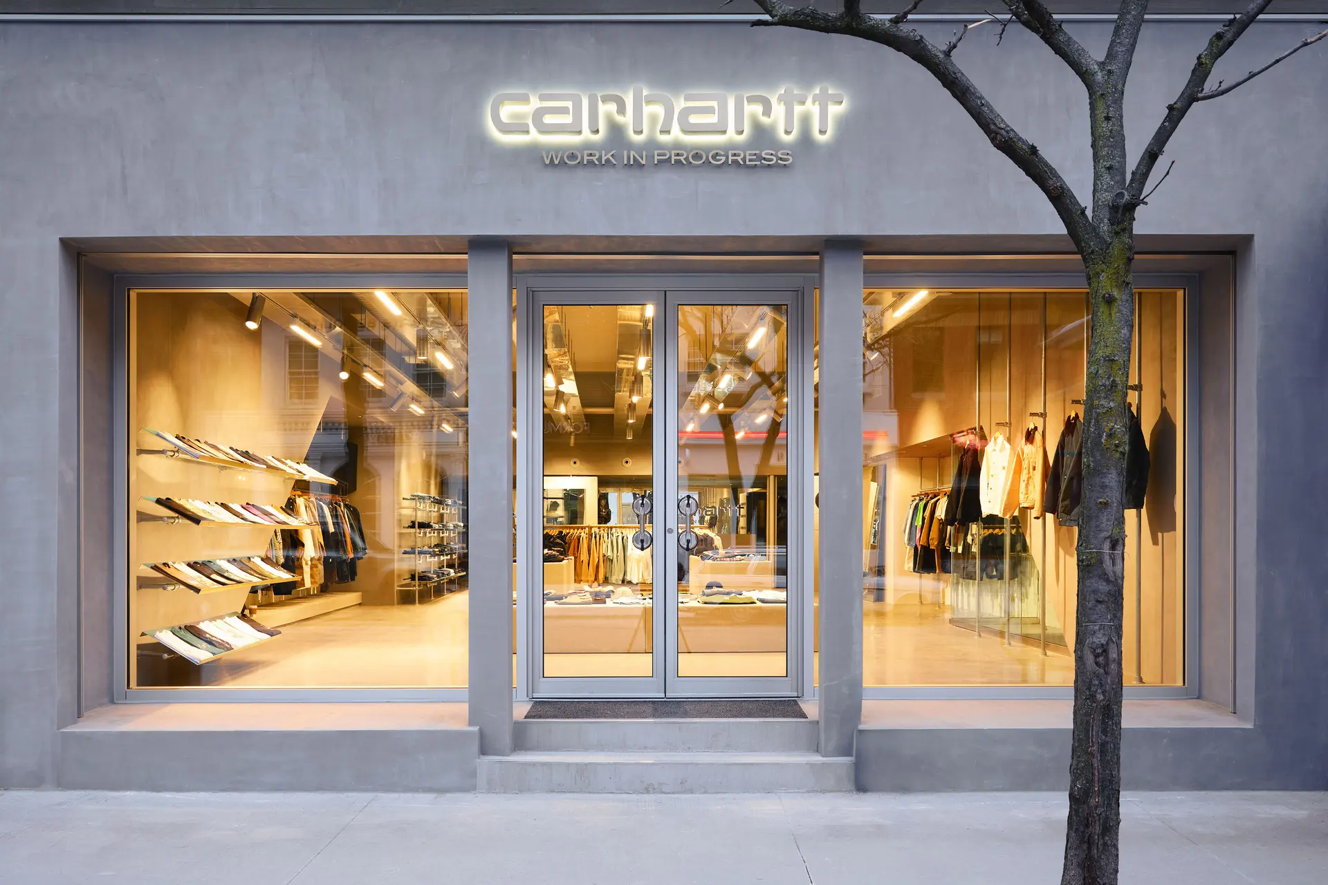 Carhartt WIP - Grey exterior with floor to ceiling windows looking into a brightly lit store with clean rows of clothing | Homes Almanac