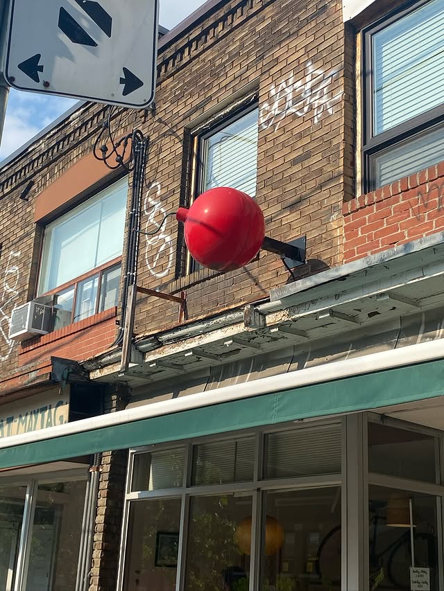 Cherry Bomb Coffee | Brick facade with a red bomb art installation over a green awning on a sunny day | Homes Almanac