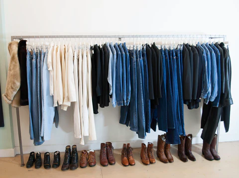 Penny Arcade | Denim neatly hung on a hangar rod against a white wall with brown shoes underneath | Homes Almanac