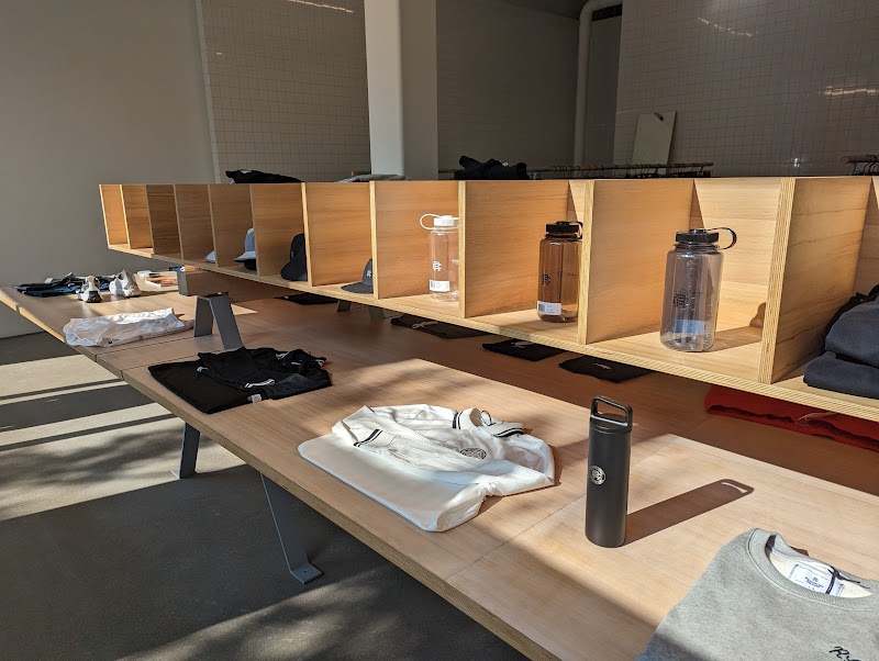 Reigning Champ | Sunlight hits a display table with neatly folded shirts and single water bottles | Homes Almanac