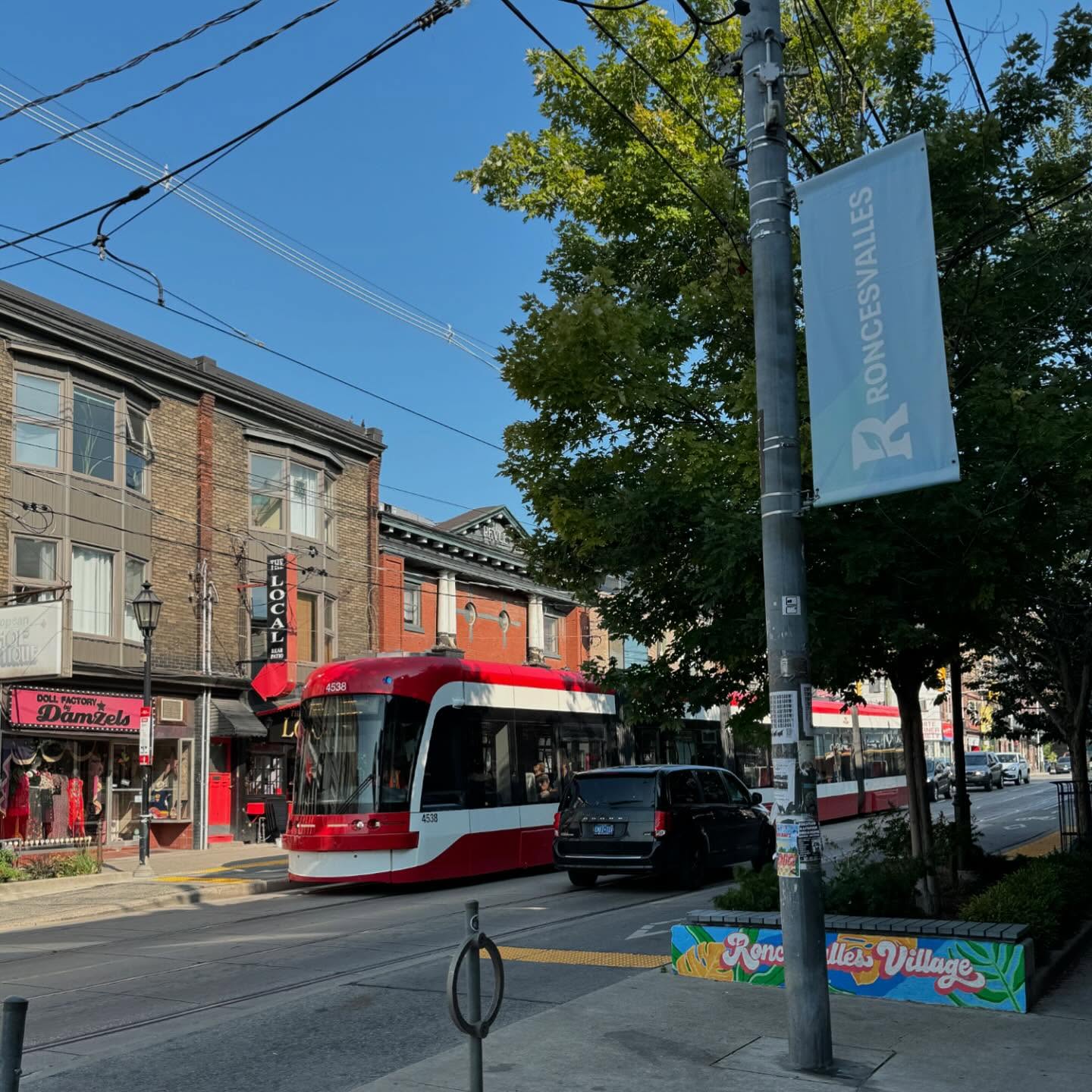 Toronto’s West End Coffee Trail: Roncesvalles Coffee Shops | Sunny day with a red streetcar on the street and a blue sign that says Roncesvalles | Homes Almanac